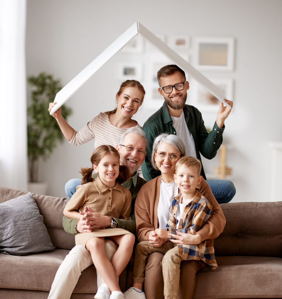 Big happy family sitting on the sofa under paper roof and smiling at camera